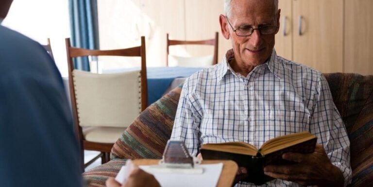 Elderly Man Reading Book in Quiet Living Area in Assisted Living Facility