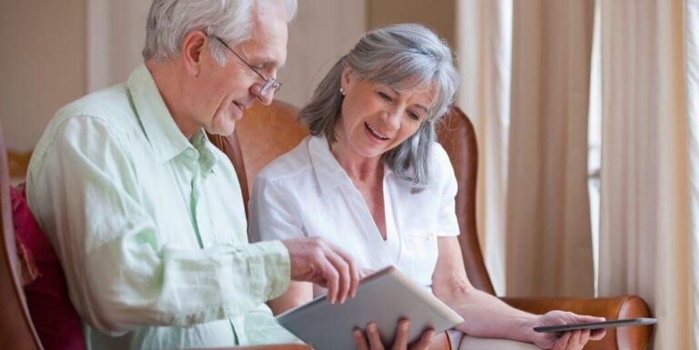 Elderly Couple Smiling While Using a Tablet Together at an Independent Living Cottages